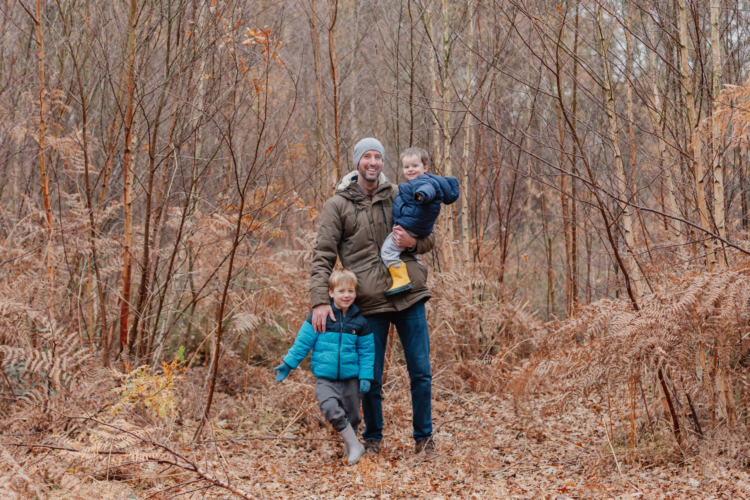 a dad and his sons in the autumn woods