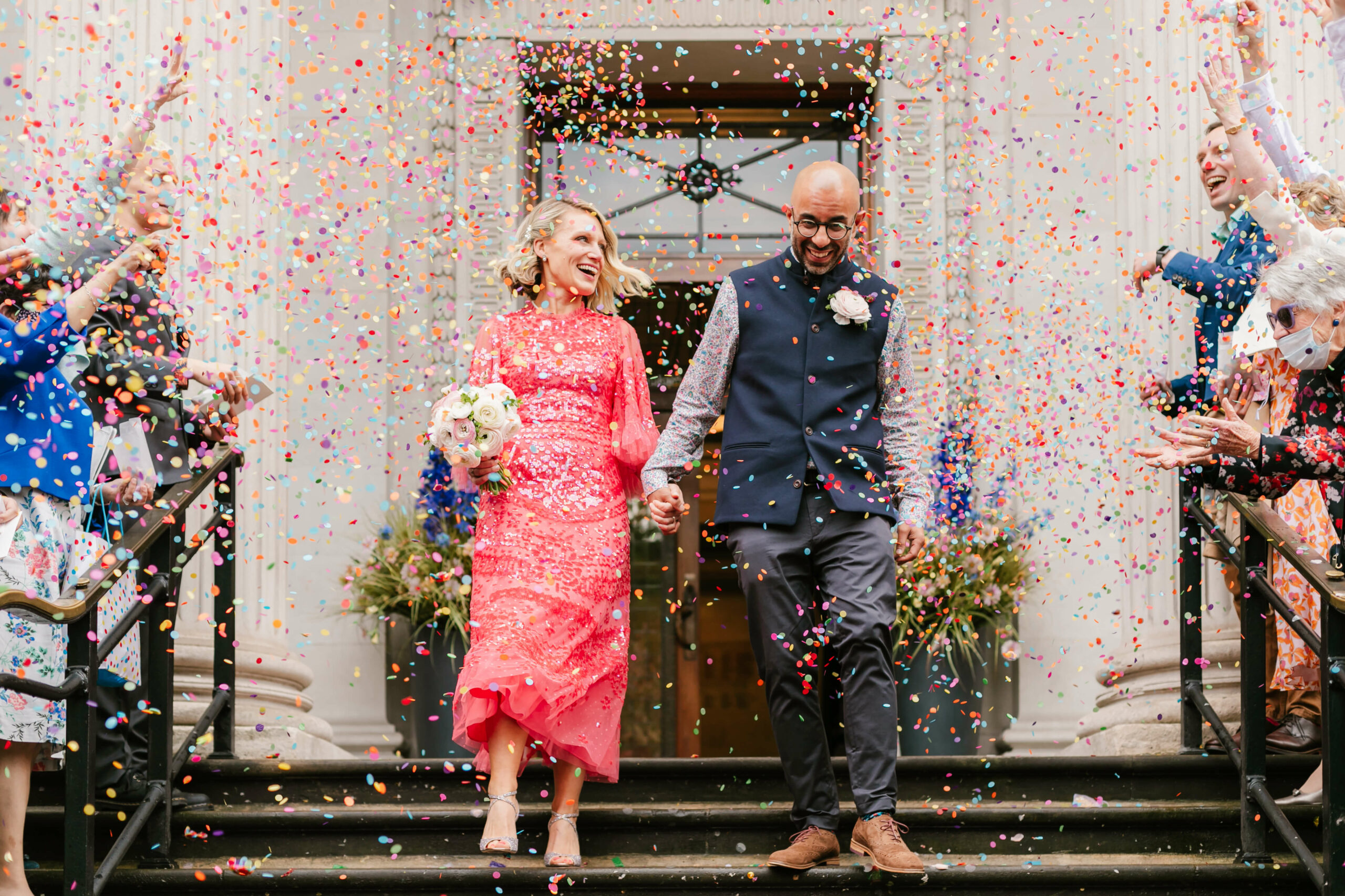 bride and groom walking down through confetti at Marylebone old town hall